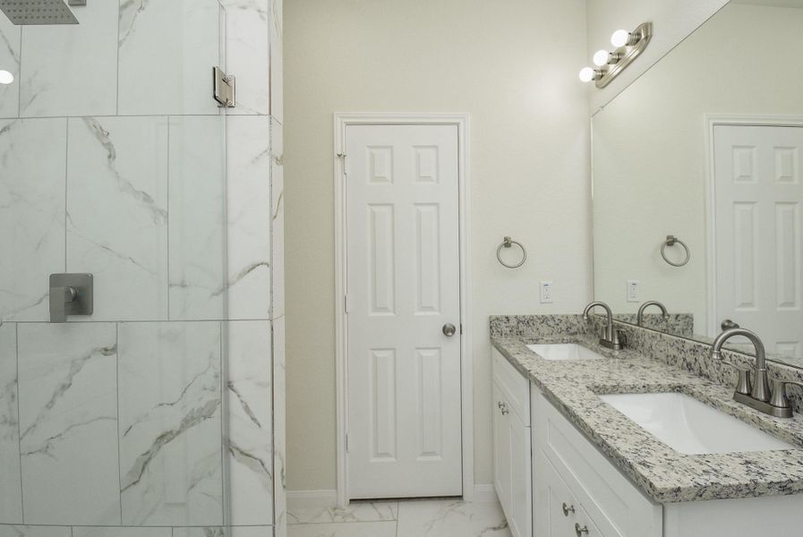 This is a modern, bright bathroom with marble-style tiling, featuring a large walk-in shower and vanity with ample counter space. There are two windows providing natural light. This is a modern, bright bathroom with marble-style tiling, featuring a large walk-in shower and vanity with ample counter space. There are two windows providing natural light.
