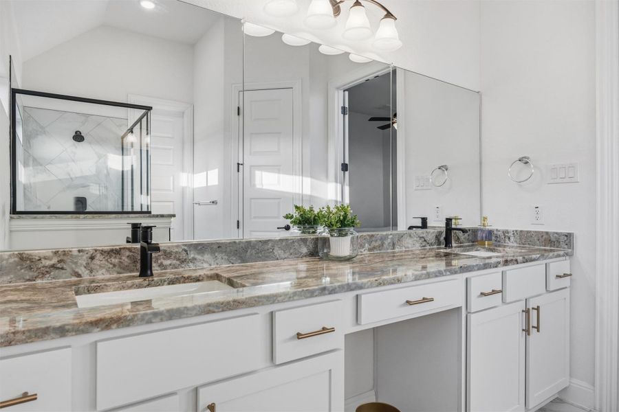 Full bath featuring double vanity, a shower stall, and vaulted ceiling