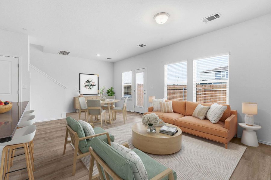 Open-concept living area featuring wood-finish flooring, white walls, and multiple windows with blinds Open-concept living area featuring wood-finish flooring, white walls, and multiple windows with blinds