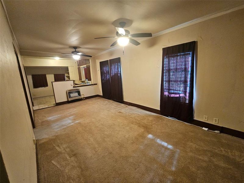 Unfurnished living room with heating unit, ceiling fan, and light colored carpet Unfurnished living room with heating unit, ceiling fan, and light colored carpet