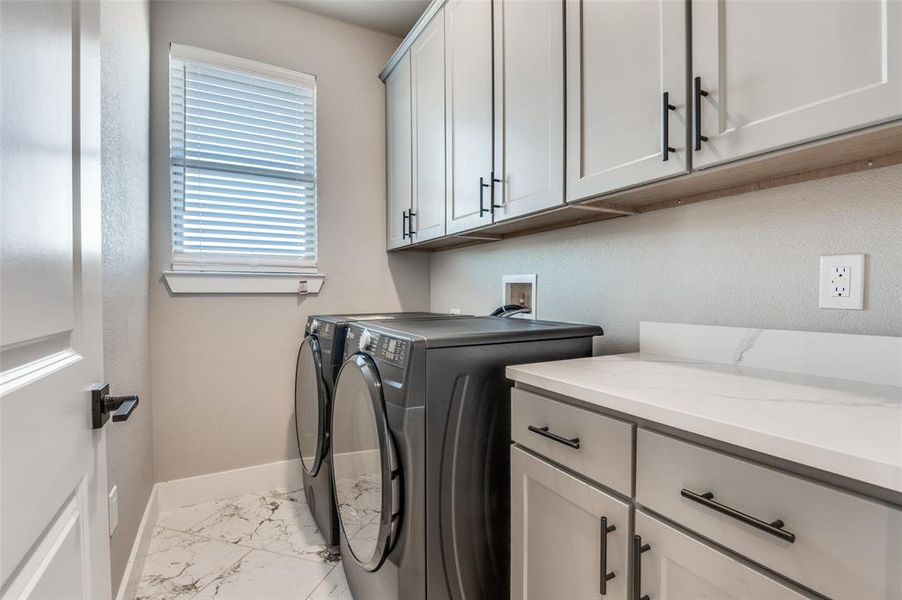 Laundry area with light marble finish flooring, cabinet space, and washing machine and clothes dryer