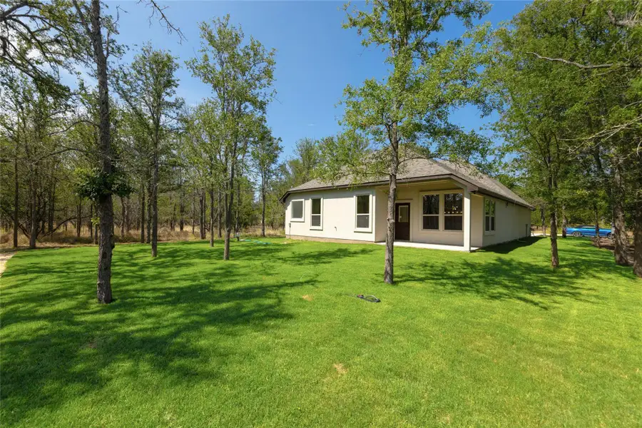 Rear view of property featuring a patio area, a yard, and stucco siding