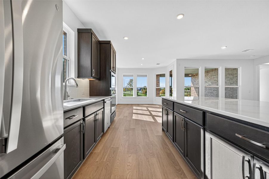 A bright, open kitchen with modern finishes and a spacious island for gathering. Sleek design meets functionality in this stylish, sunlit cooking space.