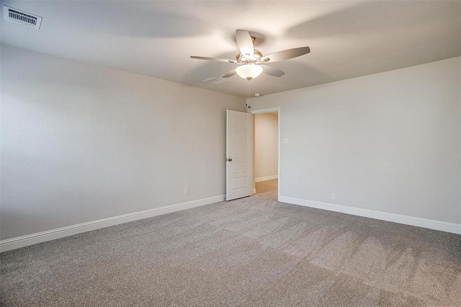 Unfurnished room featuring visible vents, ceiling fan, light carpet, and baseboards