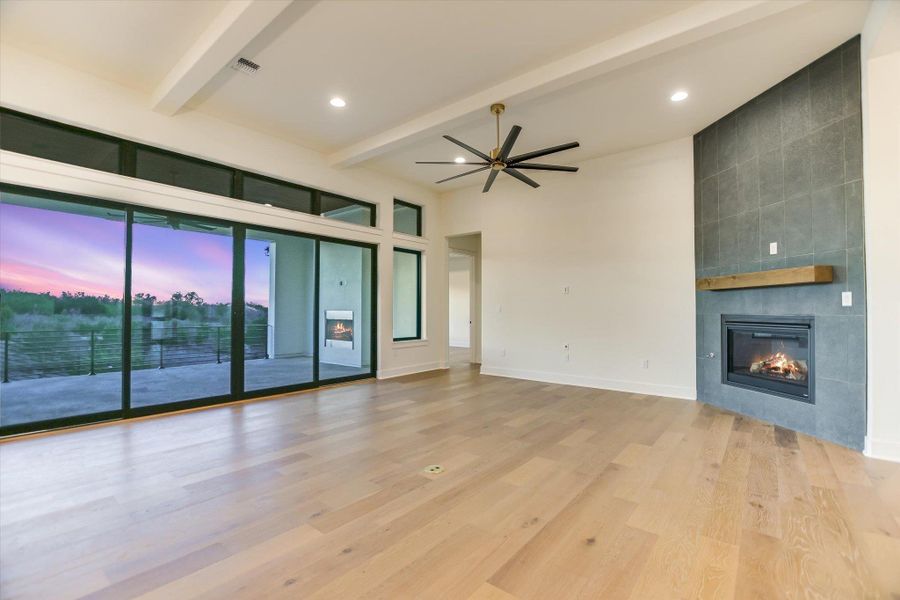 Living room featuring a fireplace, ceiling fan, light wood-type flooring, recessed lighting, and beam ceiling