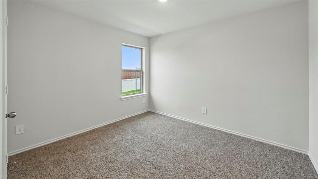 Spare room featuring dark colored carpet and baseboards
