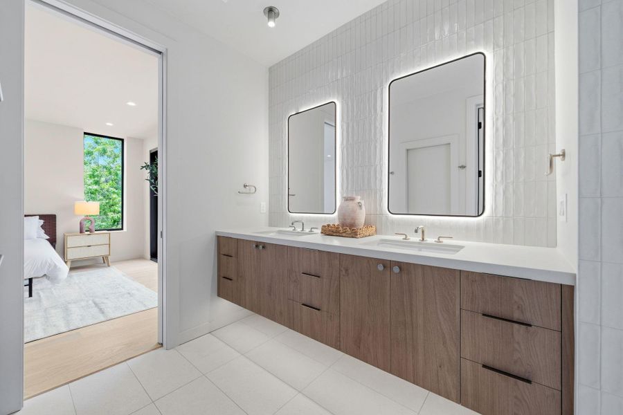 A sleek dual vanity with modern floating cabinets and illuminated mirrors awaits in this contemporary bathroom.