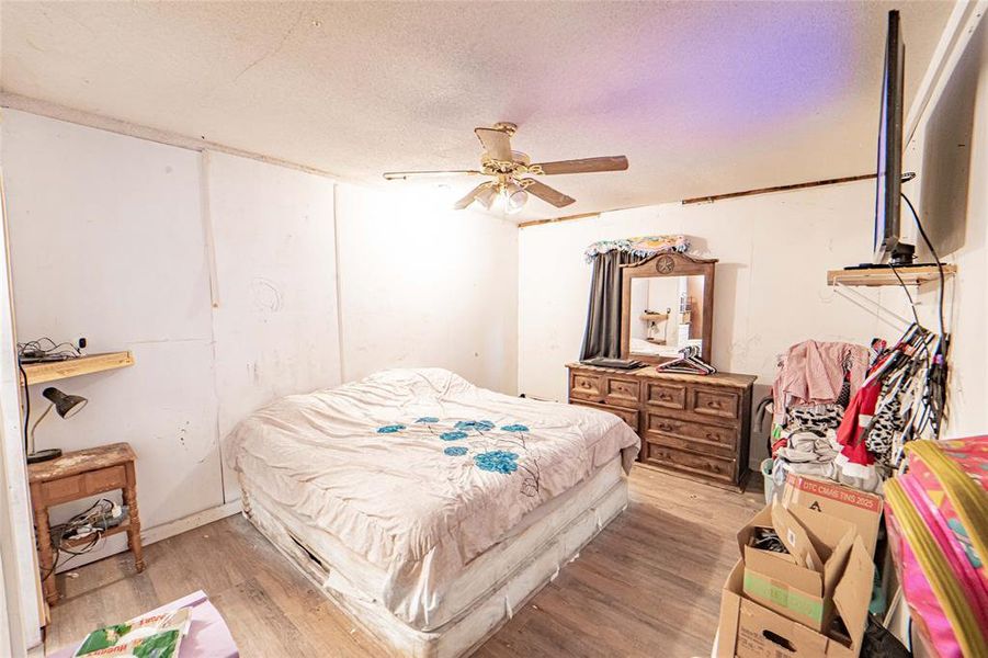 Bedroom featuring a textured ceiling, wood finished floors, and a ceiling fan Bedroom featuring a textured ceiling, wood finished floors, and a ceiling fan