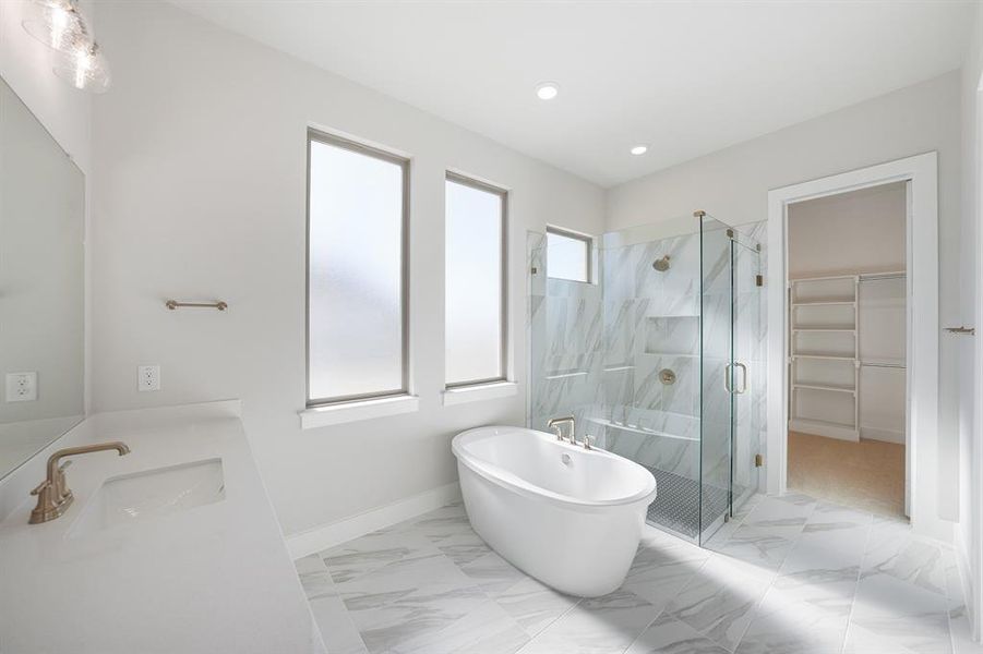 Bathroom featuring a walk in closet, double vanity, a marble finish shower, a freestanding bath, and light marble finish floors Bathroom featuring a walk in closet, double vanity, a marble finish shower, a freestanding bath, and light marble finish floors
