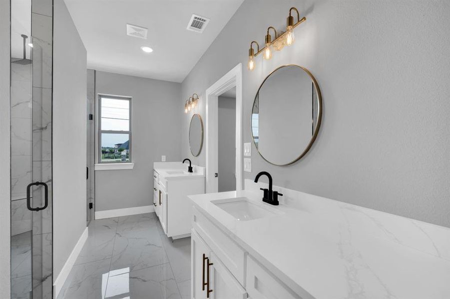 Bathroom with dual bowl vanity, tile patterned flooring, and an enclosed shower