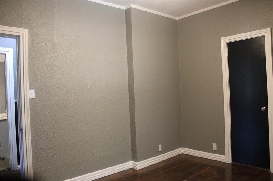 Spare room with dark wood-style floors, crown molding, and a textured wall Spare room with dark wood-style floors, crown molding, and a textured wall