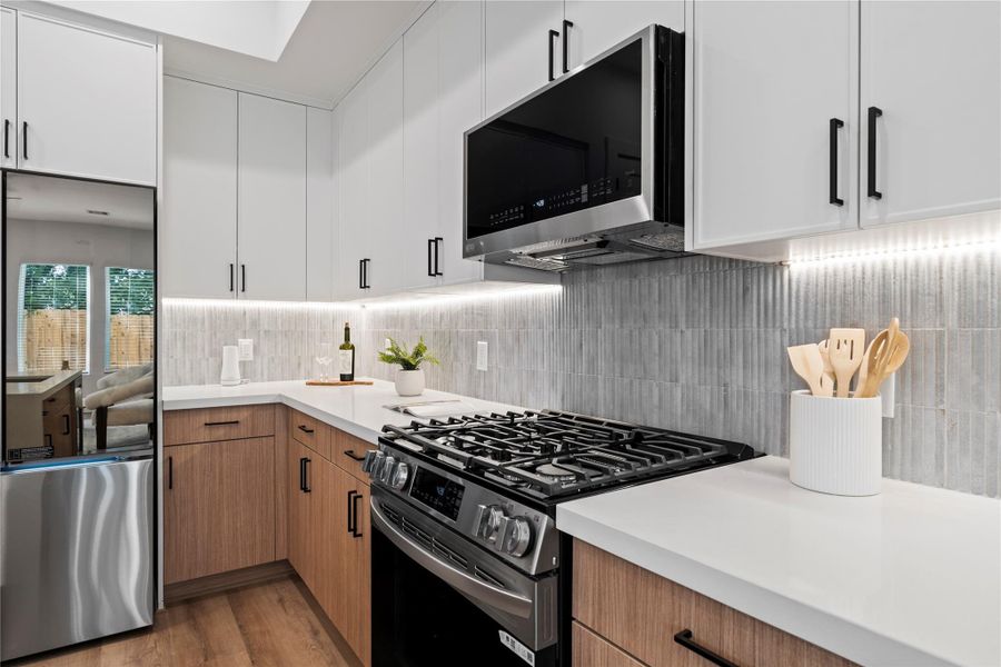 This stunning kitchen features sleek stainless steel appliances paired with white oak and white slim shaker soft close cabinetry in a blend of crisp white and warm white oak tones creates a clean, contemporary look with timeless appeal