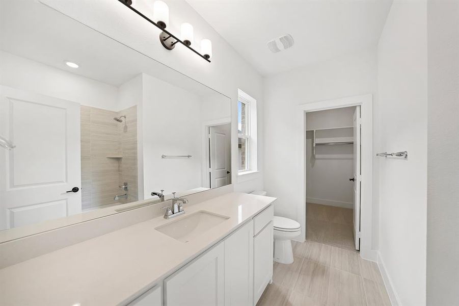 Bathroom featuring vanity, a spacious closet, tiled shower / bath combo, and light tile patterned flooring Bathroom featuring vanity, a spacious closet, tiled shower / bath combo, and light tile patterned flooring