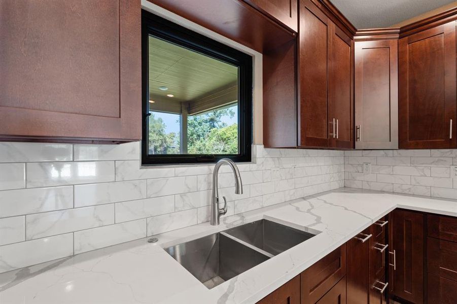 Stainless steal sink with a window overlooking the rear patio.