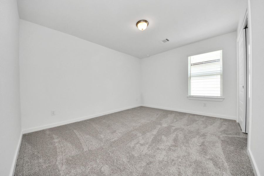 Secondary bedroom features plush carpeting, large windows that let in plenty of natural light, bright paint, and spacious closets. Sample photo of completed home with similar floor plan. Actual colors and selections may vary.