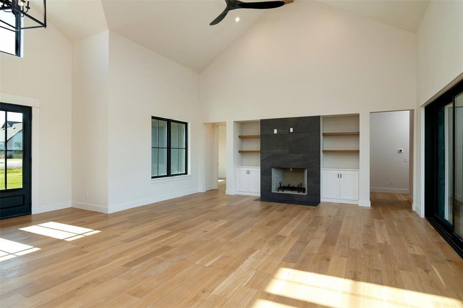 Unfurnished living room featuring light hardwood / wood-style flooring, a high end fireplace, and high vaulted ceiling