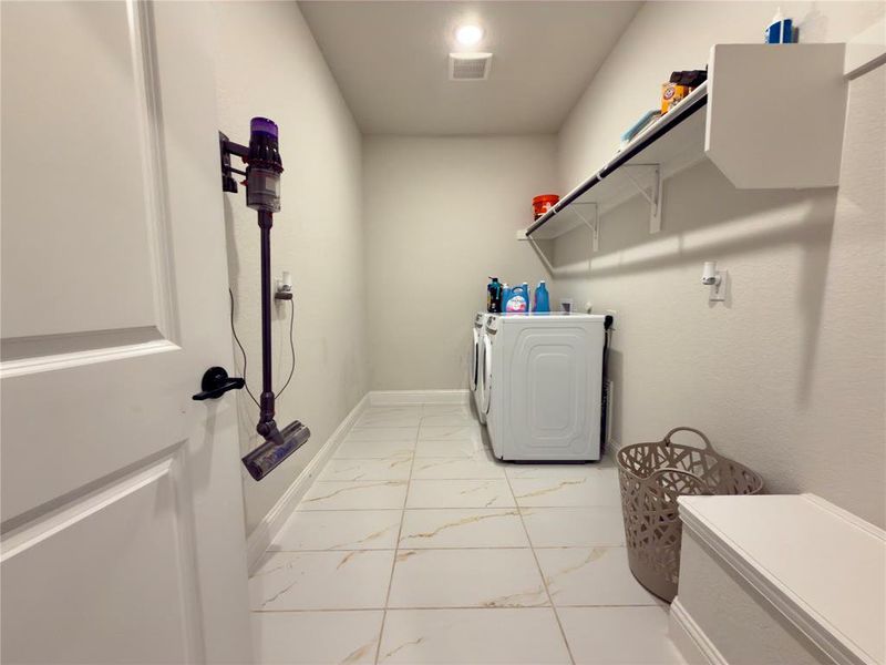 Laundry room with light marble finish flooring and washer and clothes dryer
