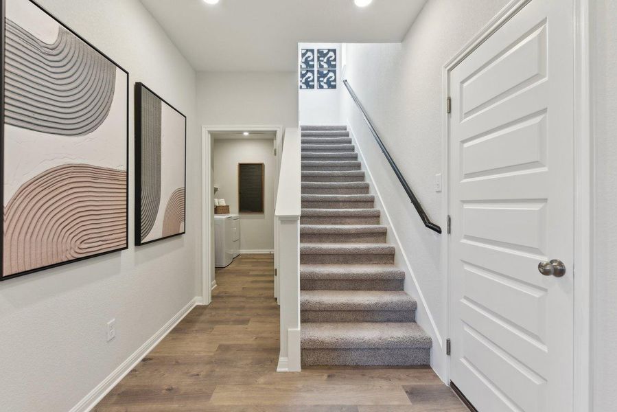 A welcoming entry hall with durable flooring leads to a carpeted staircase and discreet laundry area. A welcoming entry hall with durable flooring leads to a carpeted staircase and discreet laundry area.