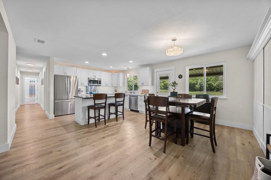 Open dining room that looks out over the kitchen, living, and backyard