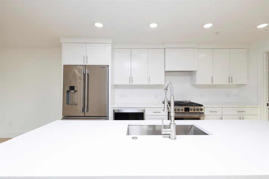 Kitchen featuring stainless steel appliances, light countertops, white cabinetry, and recessed lighting