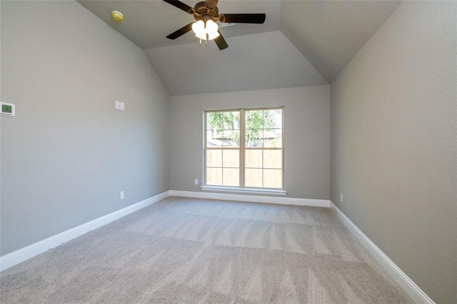 Carpeted spare room with vaulted ceiling and ceiling fan