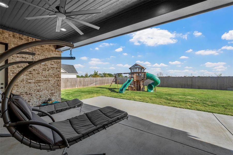 Fenced backyard featuring a patio area, a playground, outdoor lounge area, and a ceiling fan Fenced backyard featuring a patio area, a playground, outdoor lounge area, and a ceiling fan