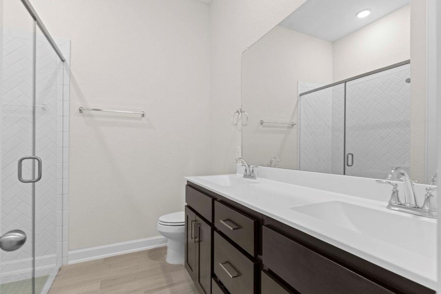 Secondary bath with dual vanities, framed mirror, and a sleek glass-enclosed shower, combining style with everyday convenience.  What I like is all the draws and cabinets this vanity has!