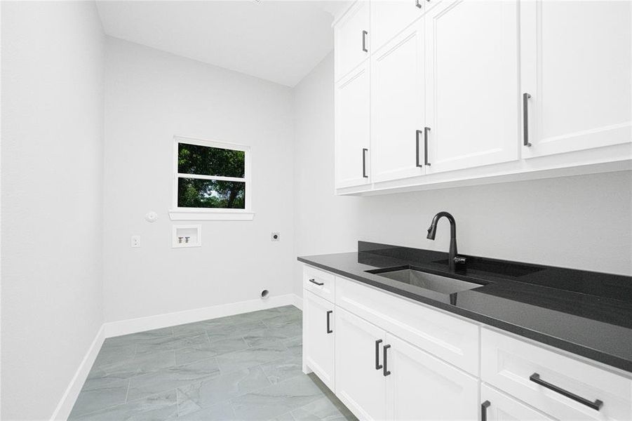 Washroom featuring cabinet space, baseboards, hookup for a washing machine, hookup for an electric dryer, and light marble finish flooring Washroom featuring cabinet space, baseboards, hookup for a washing machine, hookup for an electric dryer, and light marble finish flooring