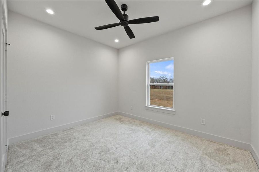 Empty room with light colored carpet and ceiling fan