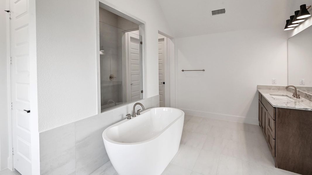 Full bathroom featuring toilet, vanity, a stall shower, and a textured wall