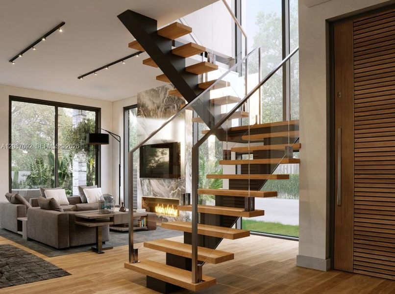 Floating staircase with wood treads and glass railing, wide plank wood-finish flooring, full-height windows, built-in fireplace with stone surround, and flush-mounted ceiling lighting