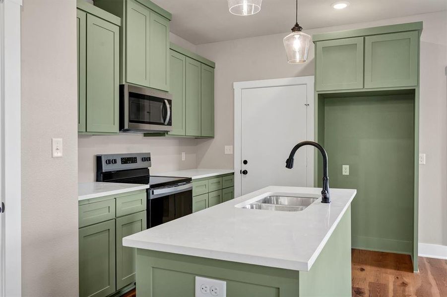 Kitchen with green cabinetry, stainless steel appliances, pendant lighting, dark wood finished floors, and recessed lighting