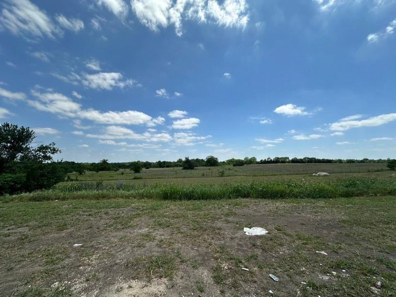 Expansive rural land featuring open fields and mature trees along the perimeter