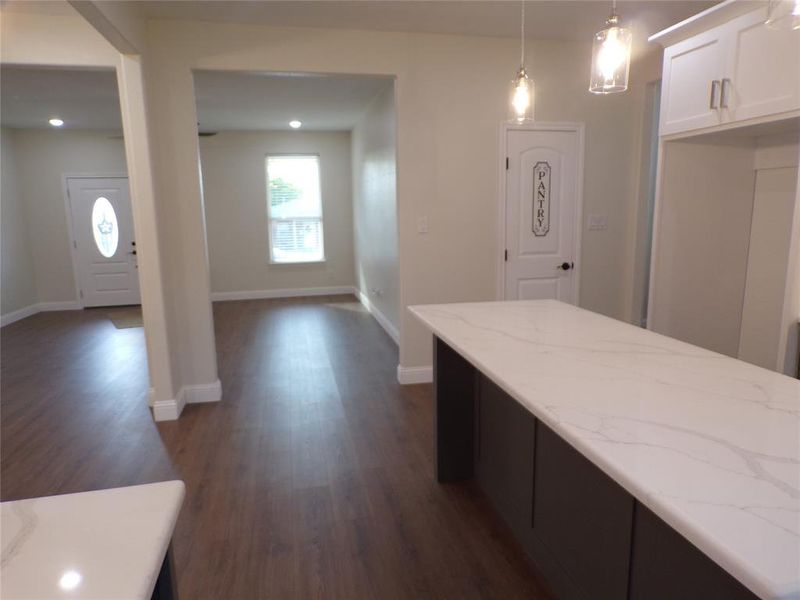 Kitchen featuring light stone counters, decorative light fixtures, dark hardwood / wood-style flooring, and white cabinetry