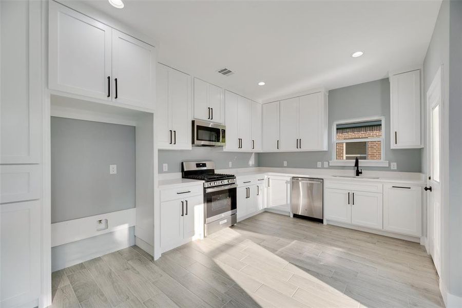 Kitchen featuring white cabinetry, light hardwood / wood-style flooring, appliances with stainless steel finishes, and sink