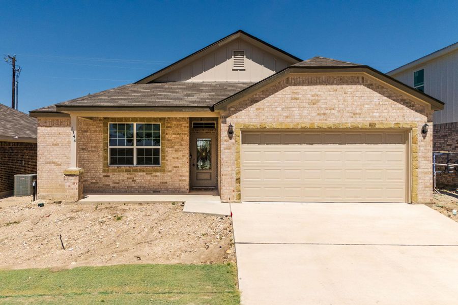 View of front of property featuring board and batten siding, an attached garage, driveway, and brick siding