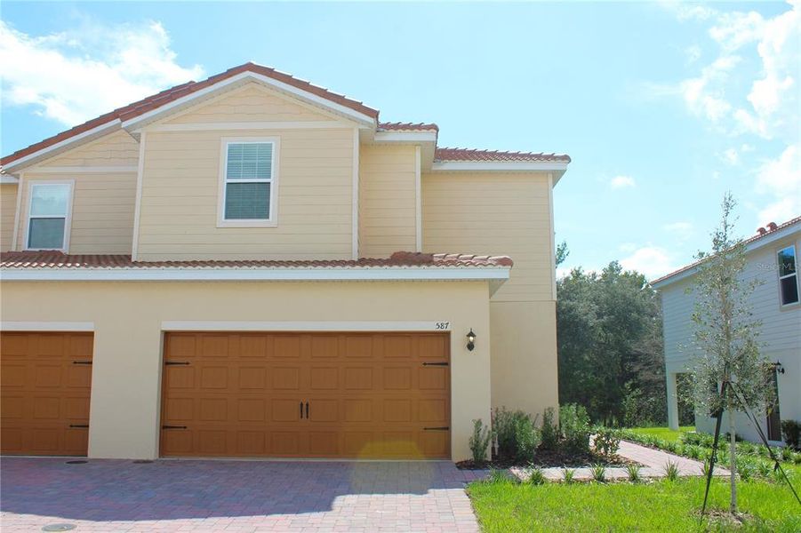 Front exterior of a new home in Noah Estates at Tuscany Preserve, Poinciana, FL, highlighting curb appeal (Image 1).