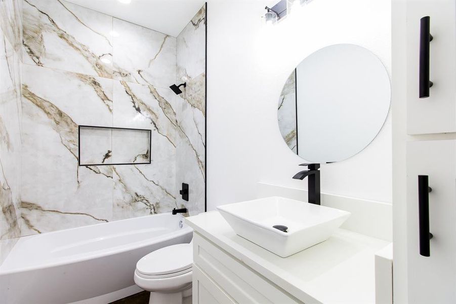 Full bathroom with vanity, tiled shower / bath combo, and toilet