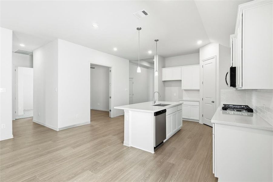 Kitchen featuring hanging light fixtures, an island with sink, white cabinets, and recessed lighting