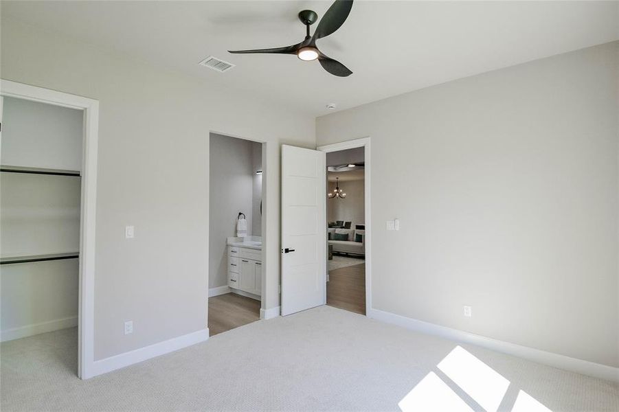 Unfurnished bedroom featuring light colored carpet, a spacious closet, ceiling fan, and connected bathroom Unfurnished bedroom featuring light colored carpet, a spacious closet, ceiling fan, and connected bathroom