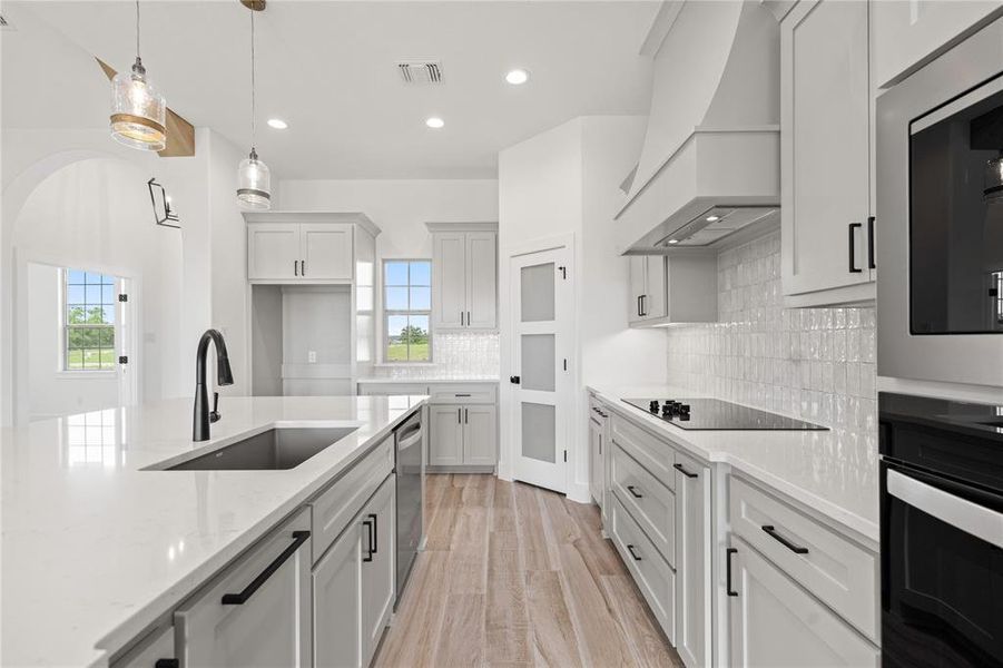 Kitchen featuring light stone countertops, tasteful backsplash, black appliances, hanging light fixtures, and recessed lighting Kitchen featuring light stone countertops, tasteful backsplash, black appliances, hanging light fixtures, and recessed lighting