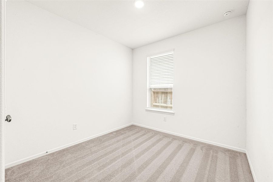 Bright and airy secondary bedroom with plush carpeting and natural light.
