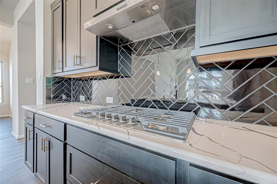 Upgraded dark cabinetry with gold hardware and a striking black hexagon subway tile backsplash.