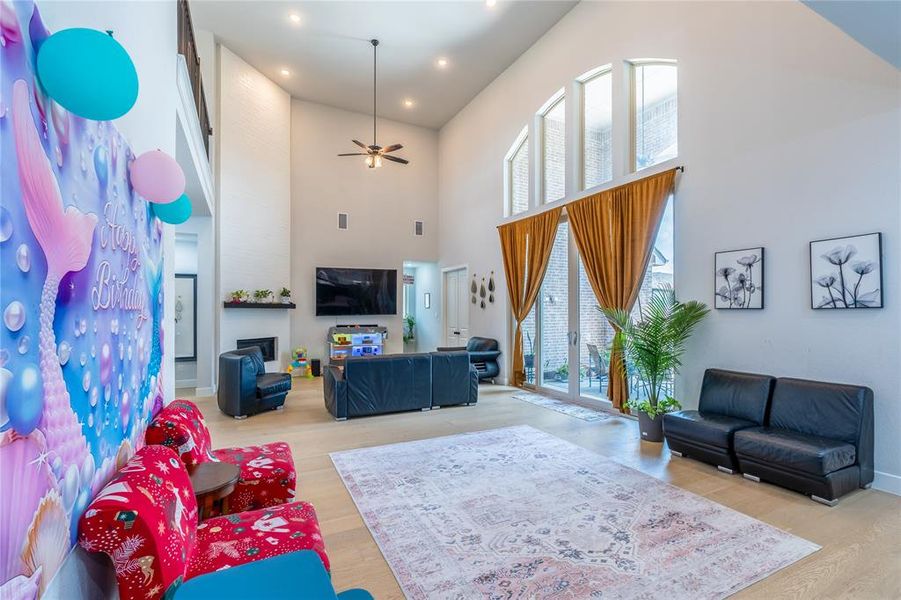 Living area featuring ceiling fan, light wood finished floors, a towering ceiling, and recessed lighting