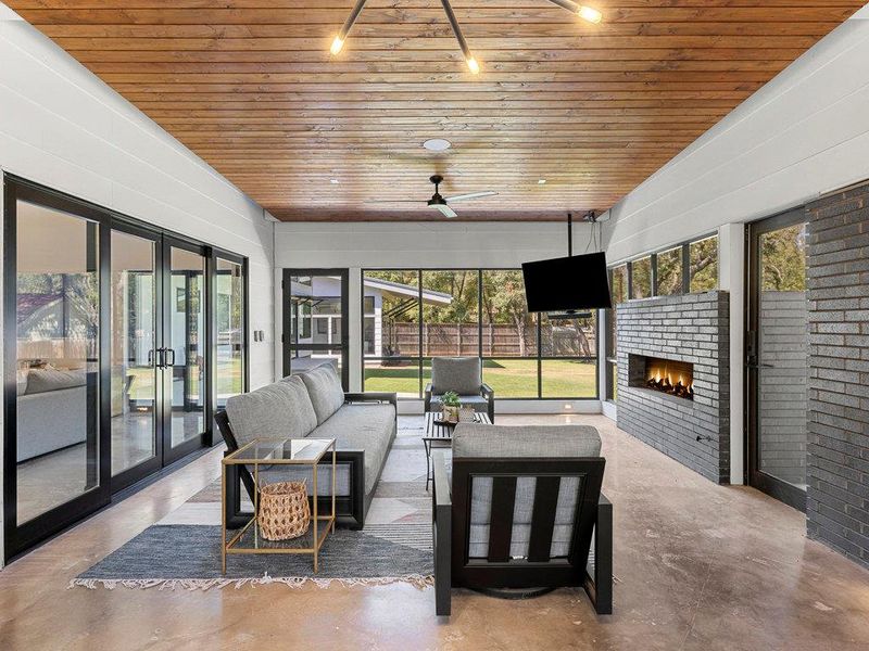 Sunroom with french doors, healthy amount of natural light, an outdoor living space with a fireplace, and ceiling fan