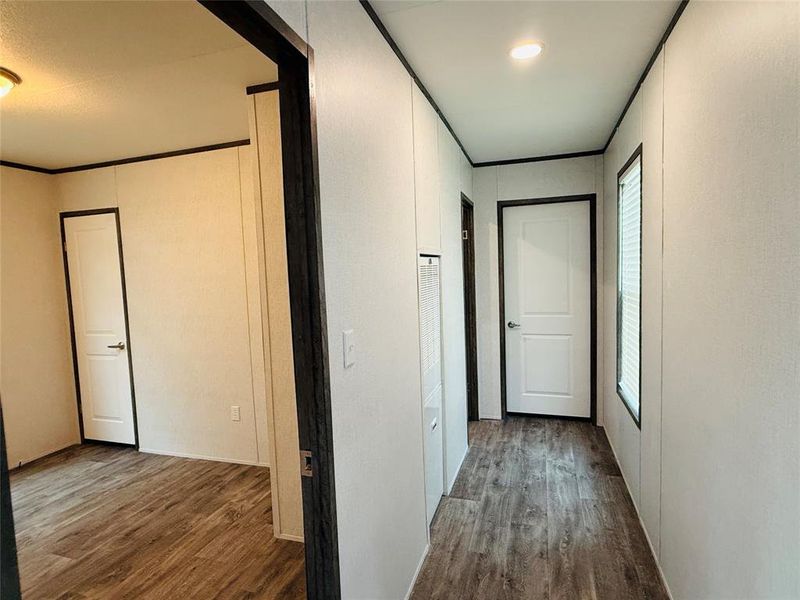Corridor featuring wood finished floors, crown molding, and plenty of natural light