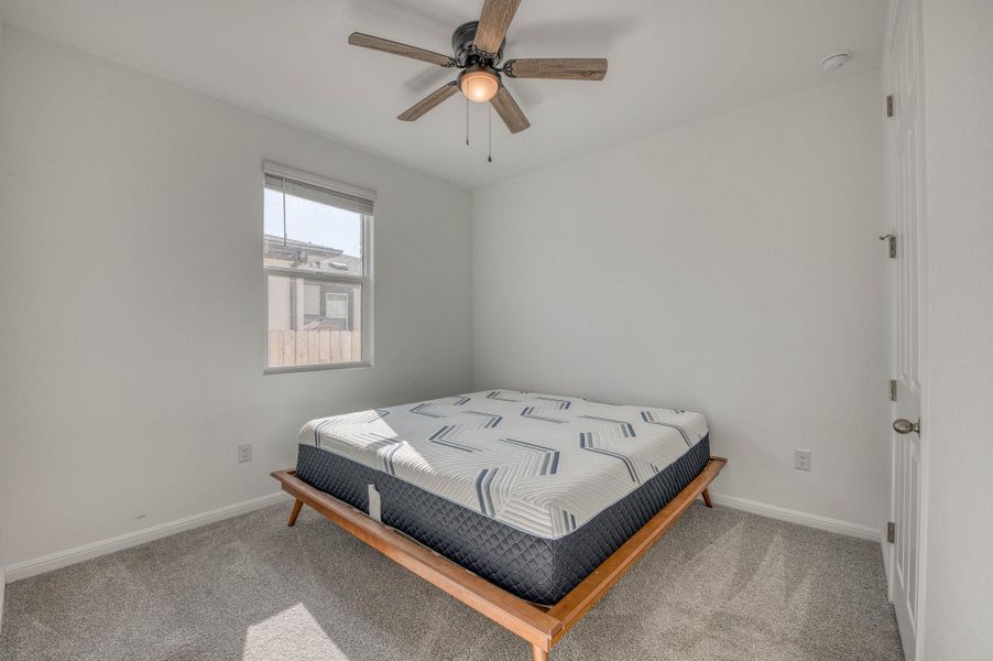 Plush carpeting and natural light define this cozy secondary bedroom space.
