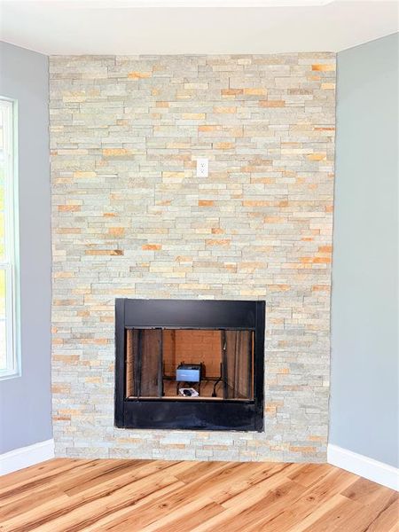 Corner fireplace featuring a stacked stone surround, a black firebox, and a visible gas connection