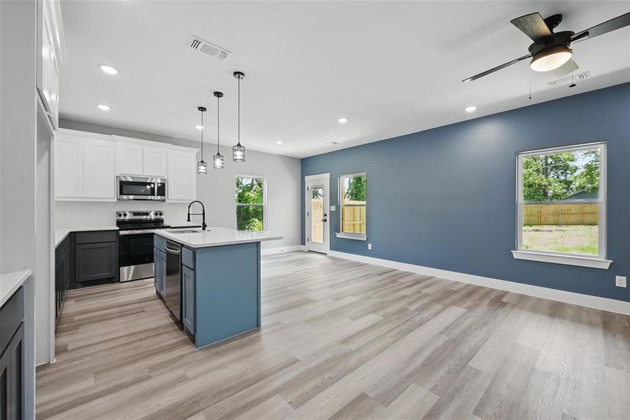 Kitchen with stainless steel appliances, a sink, light countertops, recessed lighting, and light wood finished floors