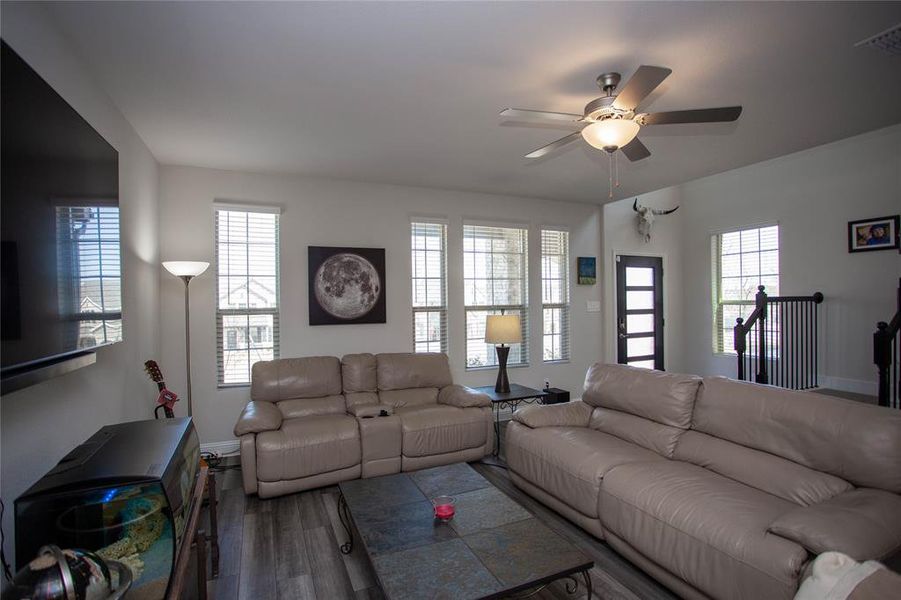 Living room with baseboards, wood finished floors, visible vents, and ceiling fan